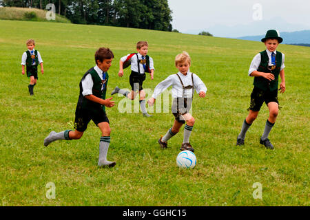 Kids in tradizionale abito bavarese a giocare a calcio, Jasberg, Dietramszell, Alta Baviera, Baviera, Germania Foto Stock