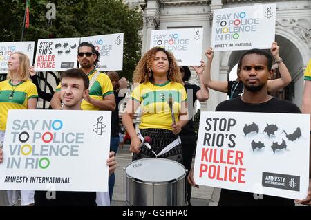 Un gruppo di dimostranti di Amnesty International protesta dichiarando 'say no alla violenza della polizia in Rio', con una banda di batteristi di Samba a Marble Arch a Londra. Foto Stock