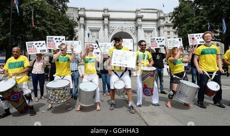 Un gruppo di dimostranti di Amnesty International protesta dichiarando 'say no alla violenza della polizia in Rio', con una banda di batteristi di Samba a Marble Arch a Londra. Foto Stock