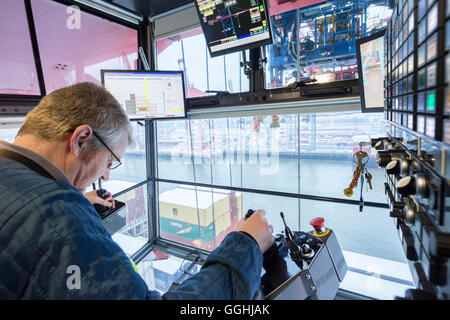 Contenitore gantry crane driver caricato e scaricato un contenitore shipt presso il terminal per container Burchardkai di Amburgo, Germania Foto Stock