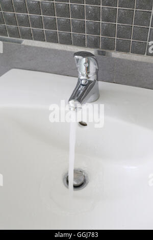 Bagno rubinetto di argento e di avere acqua che scorre nel concetto di risparmio idrico. Foto Stock