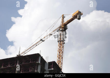 Gru lavorando su un edificio in costruzione nel tempo di giorno. Foto Stock