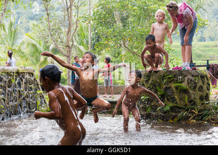 Indonesian bambini che giocano in acqua, Little Creek, saltando, spruzzi d'acqua, divertente, madre tedesca e figlio guardando, boy 3 sì Foto Stock