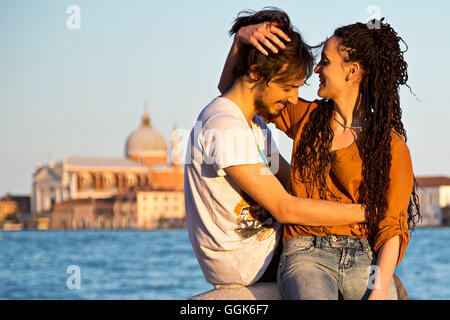 Coppia giovane kissing sulle rive del Canale della Giudecca in Dorsoduro con Chiesa del Redentore chiesa in distanza, Ve Foto Stock