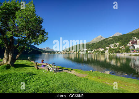 Ciclista in appoggio su una panchina in riva al lago di San Moritz, San Moritz, alta Engadina, Kanton di dei Grigioni, Svizzera Foto Stock