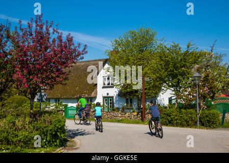 I ciclisti di fronte una casa di paglia in Nebel, Amrum Island, a nord delle Isole Frisone, Schleswig-Holstein, Germania Foto Stock