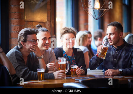 Bere nei pub alla moda giovani parlando di socializzare socializzare in chat incontro informale godendo azienda natter parlando discutere Foto Stock