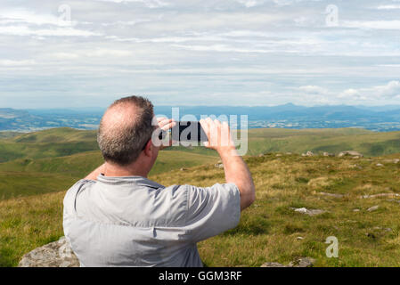 Vista dalla cima del Ben Cluech nel Ochils con la persona che utilizza il telefono cellulare per fotografare Foto Stock