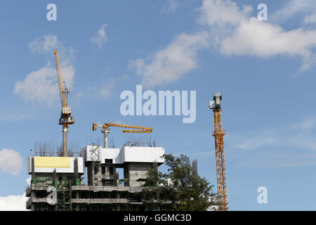 Gru lavorando su un edificio in costruzione in day time e cielo blu sullo sfondo. Foto Stock