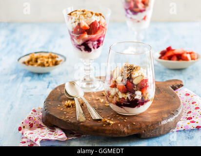 Yogurt con fragole, noci e semi di lino in vetro su tavola di legno, fuoco selettivo Foto Stock