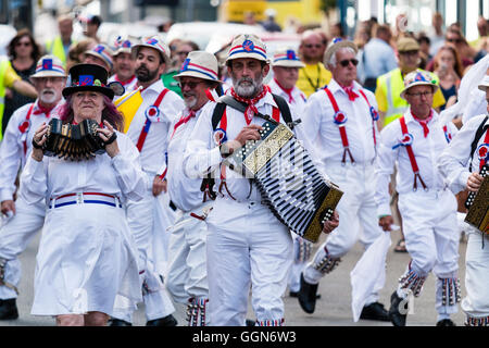 Tre morris fisarmonica giocatori che portano Hartley Morris lato come ballano sventolando hankies bianco durante una parata in città street. Venendo verso il visualizzatore. Foto Stock