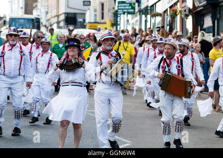 Tre morris fisarmonica giocatori che portano Hartley Morris lato come ballano sventolando hankies bianco durante una parata in città street. Venendo verso il visualizzatore. Foto Stock