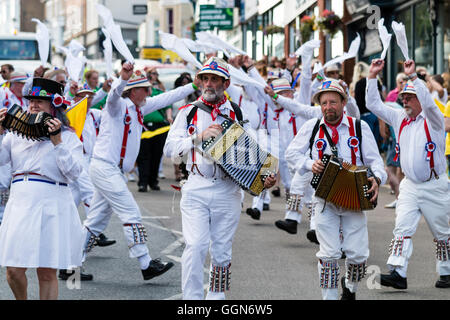 Tre morris fisarmonica giocatori che portano Hartley Morris lato come ballano sventolando hankies bianco durante una parata in città street. Venendo verso il visualizzatore. Foto Stock