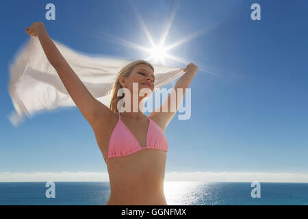 La donna caucasica in bikini azienda tessuto alla spiaggia Foto Stock