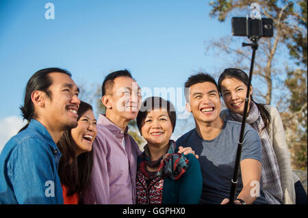 Famiglia cinese tenendo fotografia con selfie stick Foto Stock