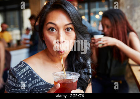 Donna di bere drink freddo con paglia in cafe Foto Stock