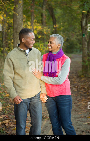 Coppia di anziani tenendo le mani a piedi nella foresta Foto Stock