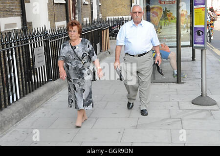 Un anziana coppia italiana a piedi lungo London's Clerkenwell Road, dopo aver trascorso un pomeriggio in un italiano festival religioso. Foto Stock