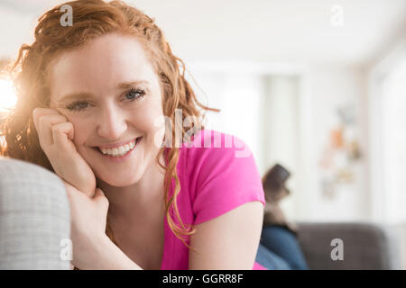 Sorridente donna caucasica la posa sul divano Foto Stock