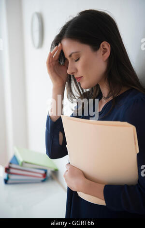 Imprenditrice caucasici con mal di testa tenendo la cartella dei file di Office Foto Stock