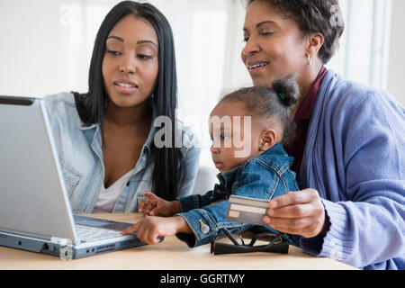 Nero multi-generazione famiglia shopping online utilizzando laptop Foto Stock