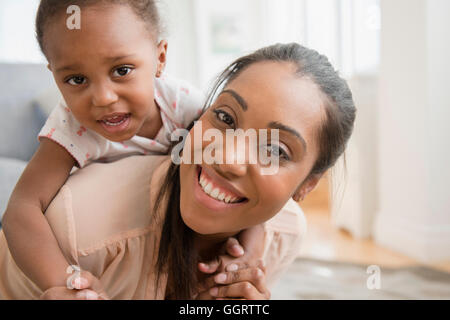 Madre nera bambino portando la figlia piggyback Foto Stock