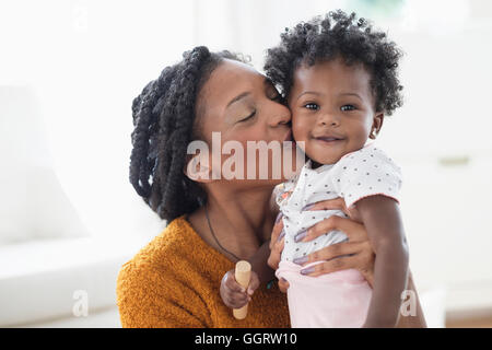 Sorridente madre nera baciando la nostra bambina sulla guancia Foto Stock