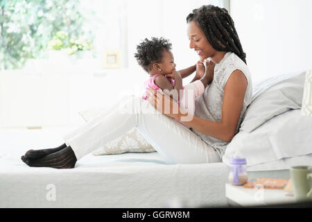 Nero donna cuddling con la nostra bambina sul letto Foto Stock