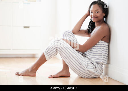 Nero sorridente donna seduta sul pavimento Foto Stock