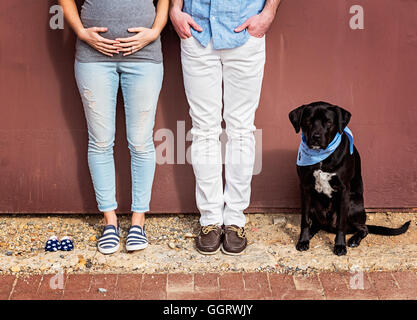 Uomo caucasico e madre in attesa con il cane e scarpe per bambini Foto Stock