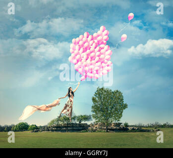 Donna cinese che viene sollevato in campo da bouquet di palloncini rosa Foto Stock