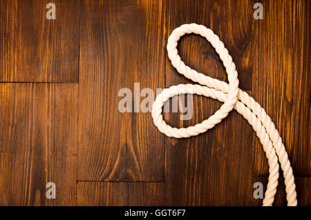 Corda di iuta nel cuore sagomata su sfondo di legno Foto Stock