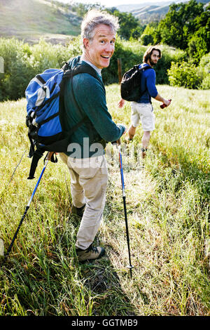 Uomini caucasici escursionismo in erba sulla montagna Foto Stock