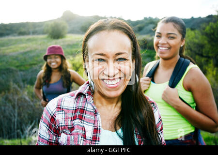 Razza mista la madre e le figlie backpacking nel campo Foto Stock