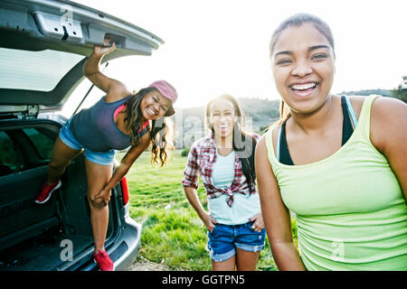 Razza mista la madre e le figlie al portello di macchina ridendo Foto Stock