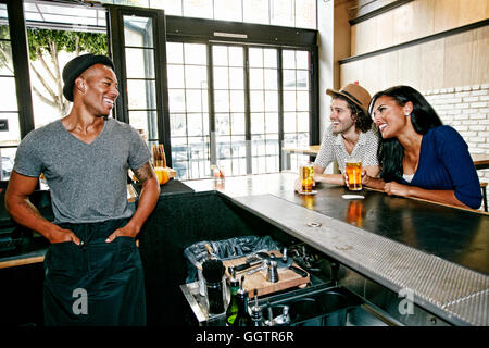 Barman sorridenti e i clienti al bar Foto Stock