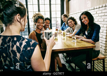 Cameriera serve sorridendo gli amici a tavola in bar Foto Stock
