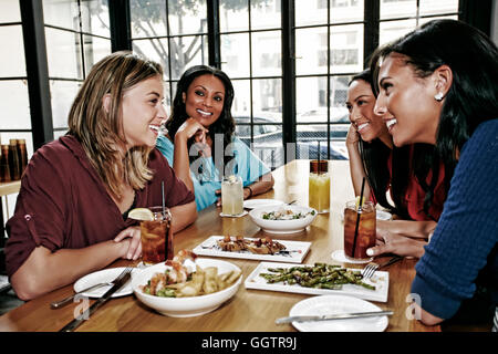 Sorridente amici gustando cibi e cocktail a tavola in bar Foto Stock