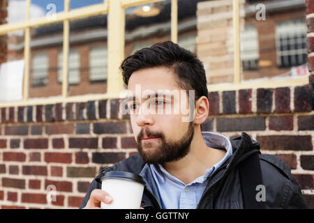 Uomo ispanico la sacca di custodia di bere il caffè in città Foto Stock