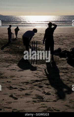 Solo su una spiaggia inglese... questi stagliano figure sta giocando la quintessenza Inglese estate gioco Cricket. Foto Stock