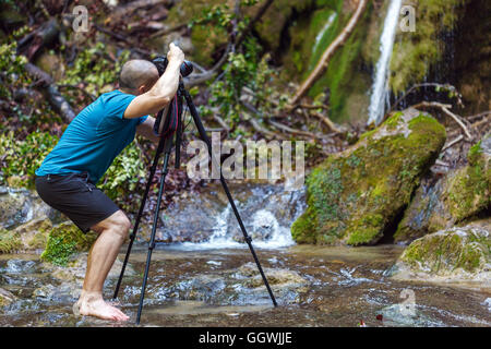 Professional fotografo di paesaggio con la fotocamera sul cavalletto la ripresa di una cascata Foto Stock