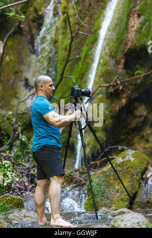 Professional fotografo di paesaggio con la fotocamera sul cavalletto la ripresa di una cascata Foto Stock