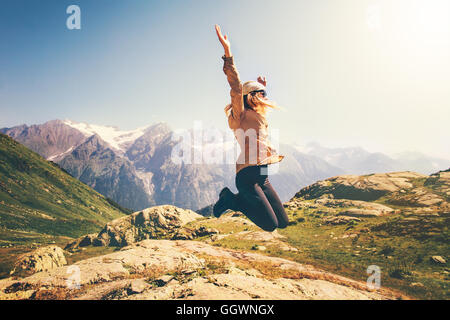 Donna felice il salto di levitazione volanti con paesaggio delle montagne sullo sfondo dello stile di vita le emozioni di viaggio il concetto di successo outdoo Foto Stock