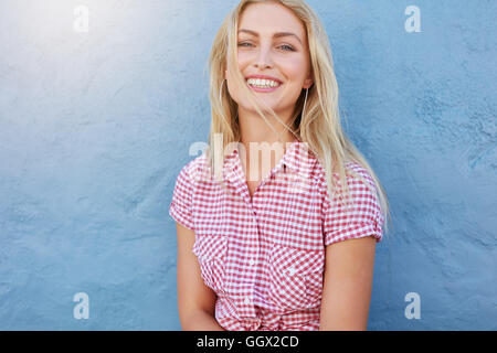 Ritratto di Allegro giovane donna che guarda la fotocamera e sorridente contro la parete di blu. Foto Stock