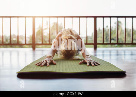 Donna facendo stretching allenamento sul tappetino fitness. Femmina Fitness eseguendo lo yoga sul tappeto di esercizio al club della salute. Foto Stock