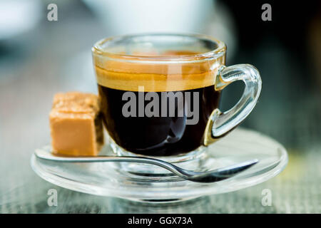 Iniziare la giornata con un preparato di fresco o reso tazza di rinfrescante forte colpo singolo caffè espresso in un bicchiere di vetro con Fudge su un tavolo e nessun popolo Foto Stock