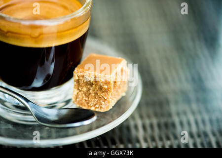 Iniziare la giornata con un preparato di fresco o reso tazza di rinfrescante forte colpo singolo caffè espresso in un bicchiere di vetro con Fudge su un tavolo e nessun popolo Foto Stock