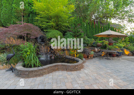 Cortile paesaggistico giardino con laghetto cascata alberi trellis impianti mobili di arredamento mattone lastricatori patio hardscape Foto Stock