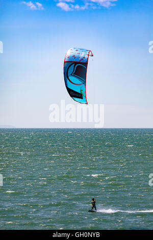 Kite boarder godendo il vento e meteo sulla spiaggia di Newborough, Anglesey, Galles, Regno Unito Foto Stock