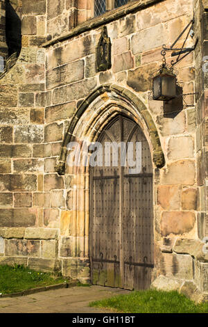 Regno Unito, Inghilterra, Cheshire, Astbury, Chiesa di Santa Maria, pesanti porte in legno di quercia e lampada Foto Stock